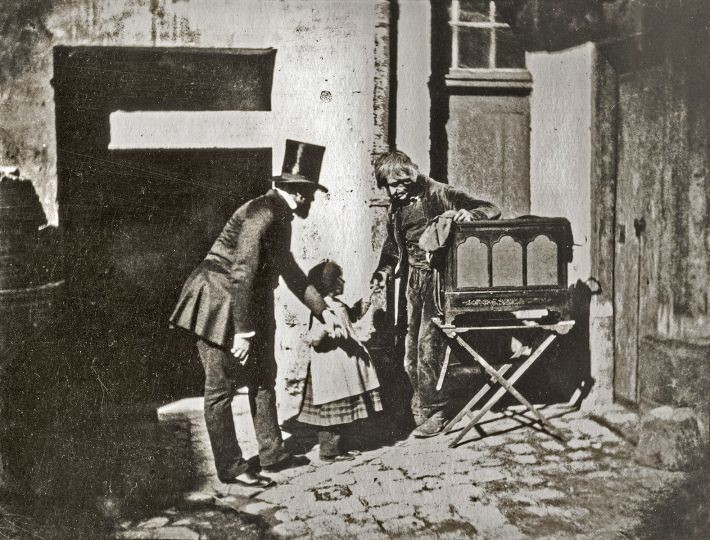 A glimpse into 19th-century street life with children interacting with a box camera, photographer unknown